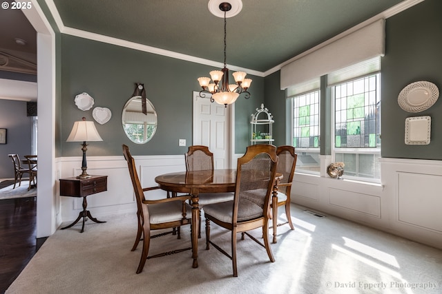 carpeted dining room featuring crown molding and a chandelier