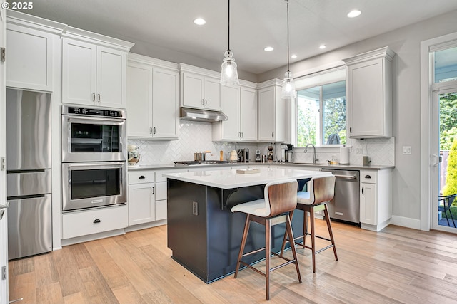 kitchen featuring backsplash, appliances with stainless steel finishes, and light wood-type flooring