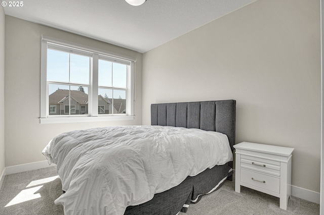 bedroom with baseboards, lofted ceiling, and light carpet