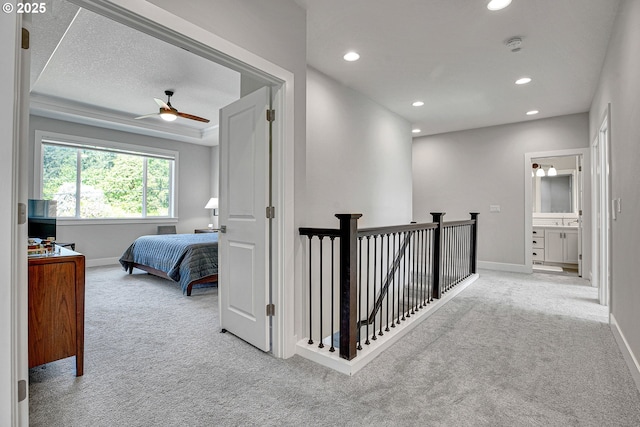 hallway with carpet floors, baseboards, recessed lighting, and an upstairs landing