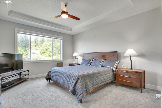 carpeted bedroom featuring crown molding, ceiling fan, a textured ceiling, baseboards, and a tray ceiling