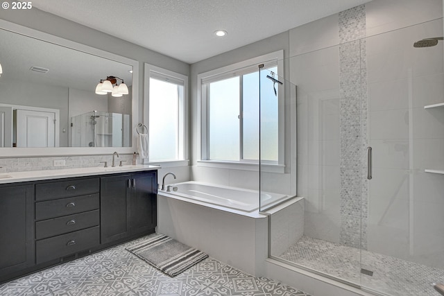 bathroom featuring a sink, double vanity, recessed lighting, a shower stall, and a garden tub