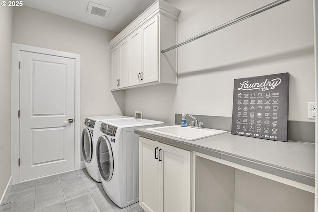 washroom featuring visible vents, washing machine and dryer, light tile patterned flooring, a sink, and cabinet space