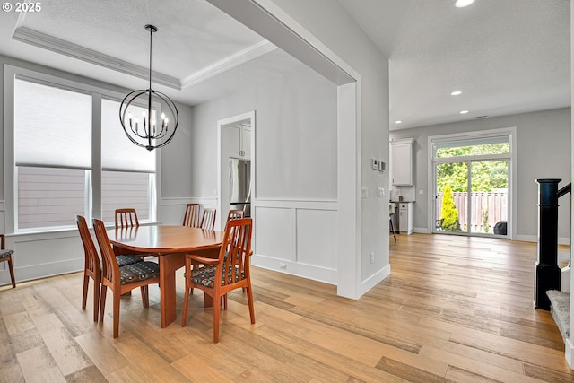 dining room with recessed lighting, an inviting chandelier, a raised ceiling, and light wood-style floors