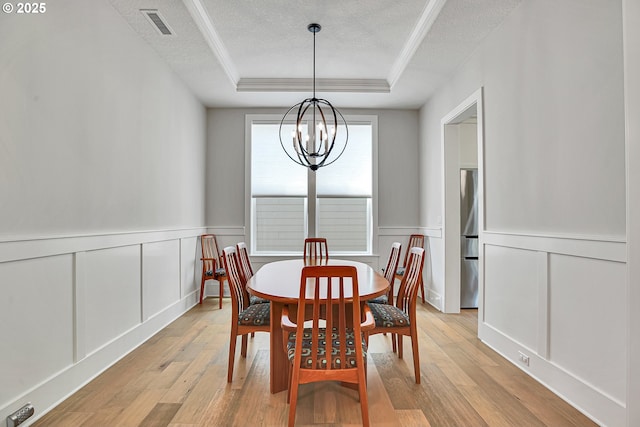 dining room featuring a decorative wall, a tray ceiling, a textured ceiling, and a notable chandelier