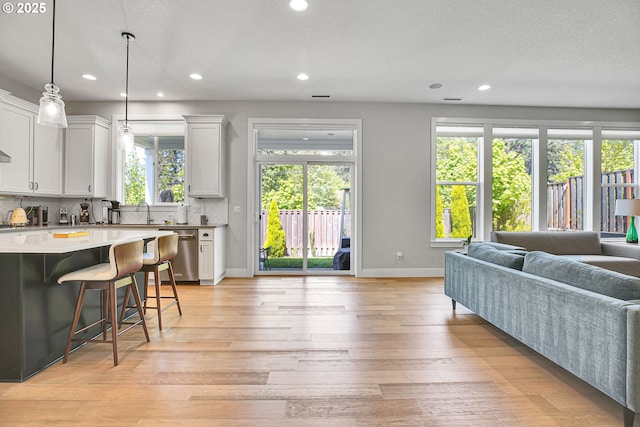 living area with baseboards, recessed lighting, and light wood-style flooring