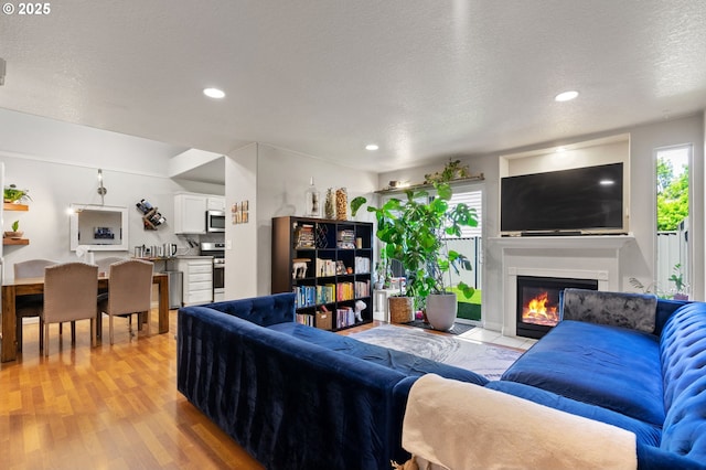 17881 SW Pars Pl, Beaverton, OR 97078 - living area featuring light wood-style floors, a glass covered fireplace, recessed lighting, and a textured ceiling