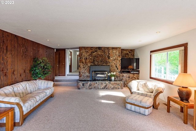 living room featuring a fireplace, carpet floors, and wood walls