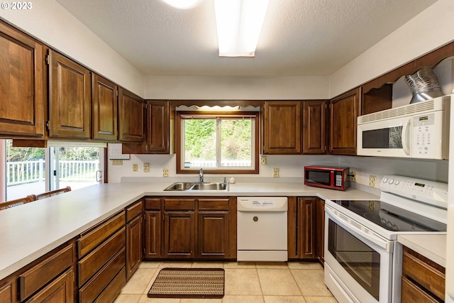 kitchen featuring sink, kitchen peninsula, a textured ceiling, white appliances, and light tile patterned floors