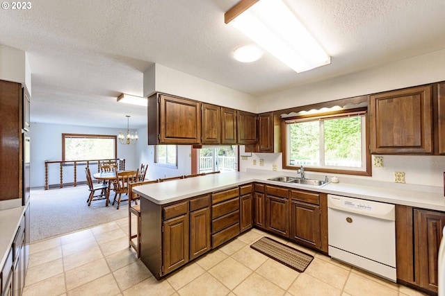 kitchen with dishwasher, sink, hanging light fixtures, kitchen peninsula, and light carpet