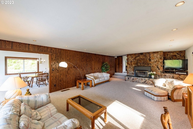 living room featuring a stone fireplace, wood walls, and carpet