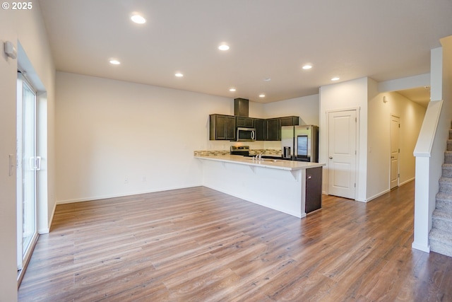 2153 NE 118th Pl, Vancouver, WA 98684 - kitchen featuring stainless steel appliances, a peninsula, light countertops, wood finished floors, and a kitchen bar