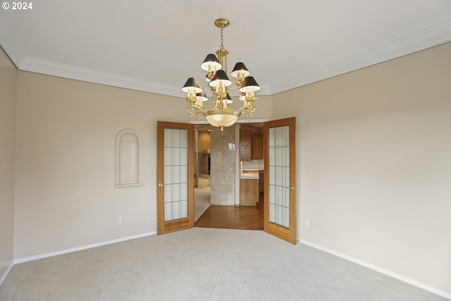 unfurnished room with an inviting chandelier, ornamental molding, carpet flooring, and french doors