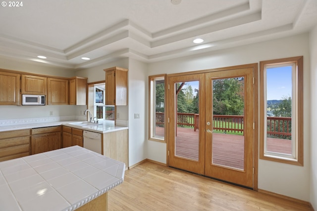 kitchen featuring sink, tile counters, white appliances, a raised ceiling, and light wood-type flooring