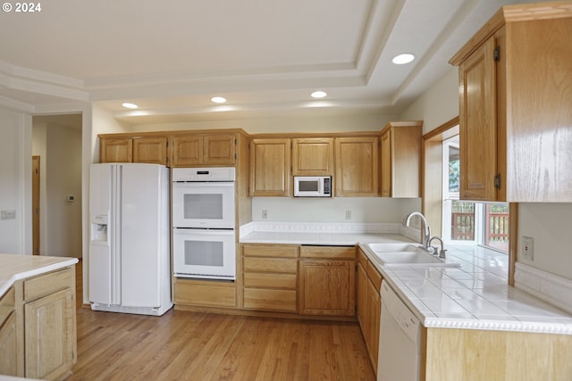 kitchen with sink, white appliances, and light hardwood / wood-style flooring