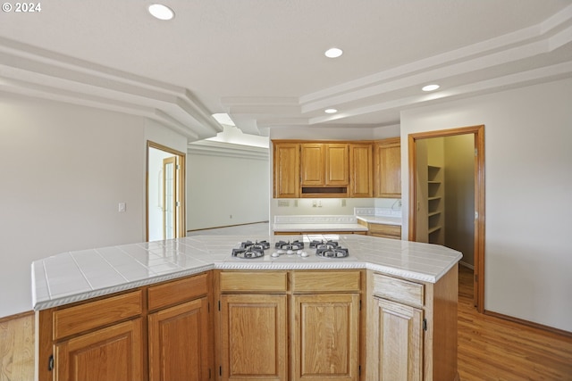 kitchen with tile counters, light hardwood / wood-style flooring, white gas cooktop, and a center island