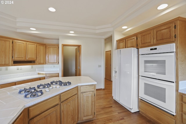 kitchen with white appliances, ornamental molding, tile countertops, and light hardwood / wood-style floors