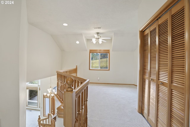 hallway featuring light carpet, lofted ceiling, and an inviting chandelier