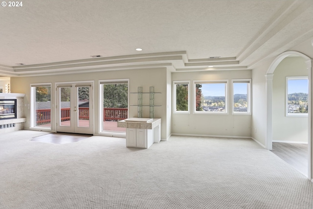 carpeted empty room featuring a raised ceiling, a textured ceiling, and french doors