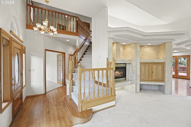 entryway featuring a chandelier, light hardwood / wood-style flooring, a high end fireplace, and french doors