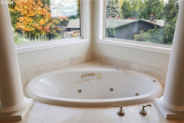 bathroom with tiled tub and ornate columns