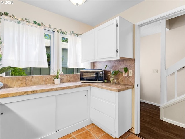 8512 SW Brightfield Cir, Tigard, OR 97223 - kitchen featuring white cabinets, stainless steel microwave, tasteful backsplash, light countertops, and baseboards