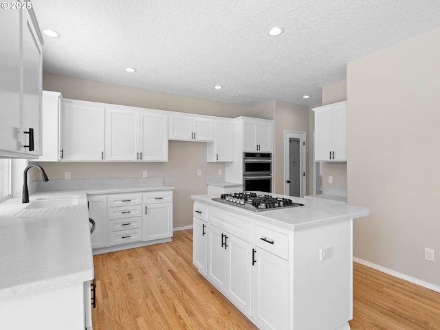 12576 NW Maplecrest Way, Banks, OR 97106 - kitchen with stainless steel appliances, light wood finished floors, a kitchen island, white cabinetry, and light countertops