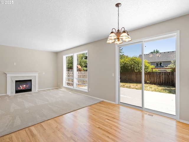 12576 NW Maplecrest Way, Banks, OR 97106 - unfurnished living room featuring wood finished floors, a high end fireplace, a chandelier, and a textured ceiling
