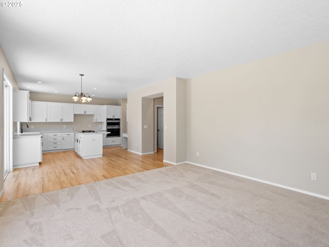 12576 NW Maplecrest Way, Banks, OR 97106 - unfurnished living room with a chandelier, light carpet, light wood-type flooring, and recessed lighting