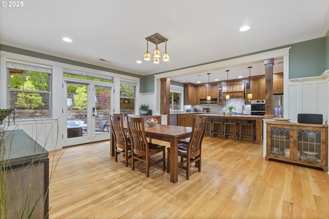 dining room featuring visible vents, light wood-style flooring, french doors, crown molding, and ornate columns