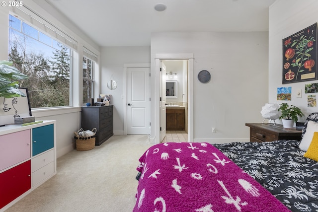 bedroom with carpet flooring, connected bathroom, baseboards, and a sink