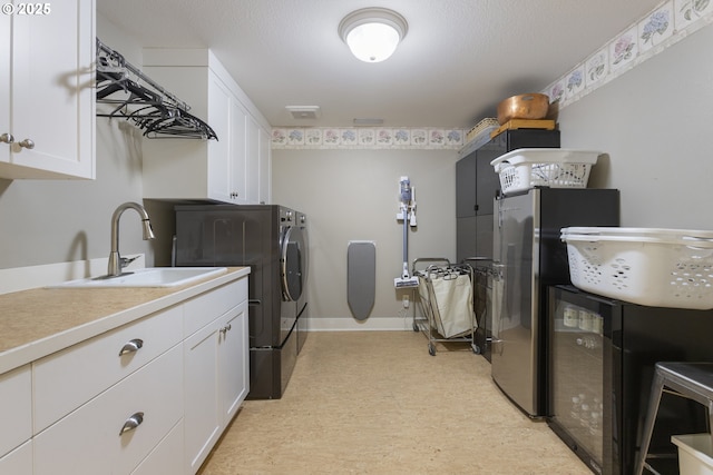 laundry area featuring a sink, washing machine and dryer, cabinet space, baseboards, and light floors