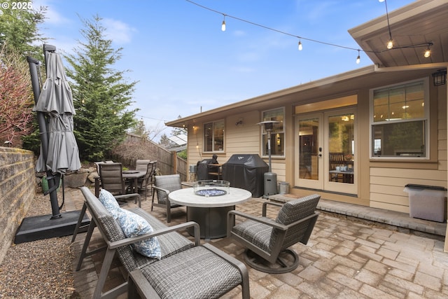 view of patio / terrace with outdoor dining space, fence, an outdoor fire pit, area for grilling, and french doors