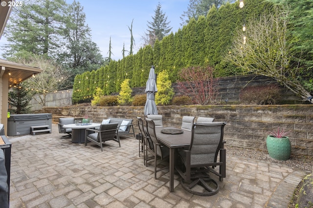 view of patio / terrace featuring outdoor dining space, a hot tub, and fence