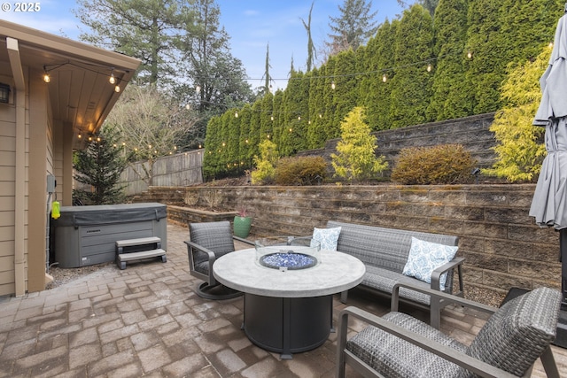 view of patio featuring a fire pit, a hot tub, and fence