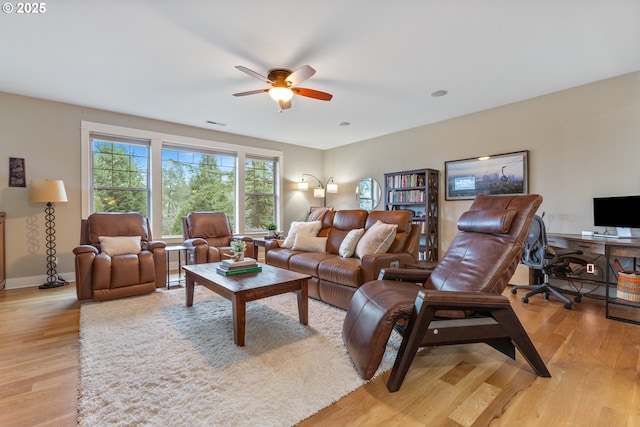 living room with visible vents, baseboards, light wood-type flooring, and a ceiling fan