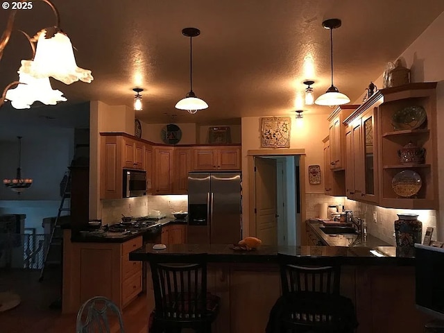 kitchen with sink, hanging light fixtures, stainless steel fridge with ice dispenser, decorative backsplash, and kitchen peninsula