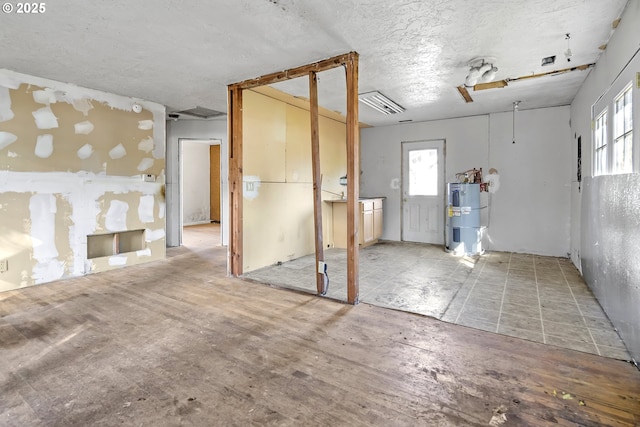 unfurnished room featuring a textured ceiling, visible vents, plenty of natural light, and electric water heater