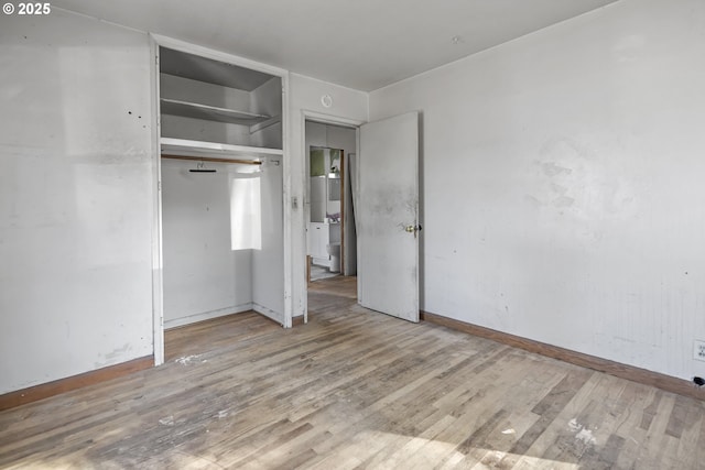 unfurnished bedroom with a closet, wood finished floors, and baseboards