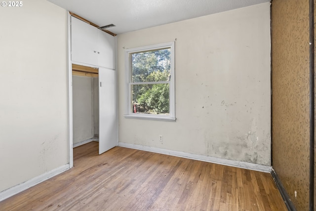 unfurnished bedroom with a closet, baseboards, and wood finished floors