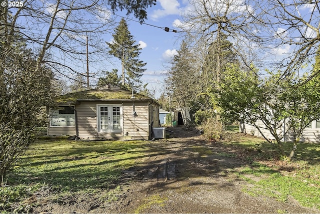 view of property exterior with a yard, french doors, and central air condition unit