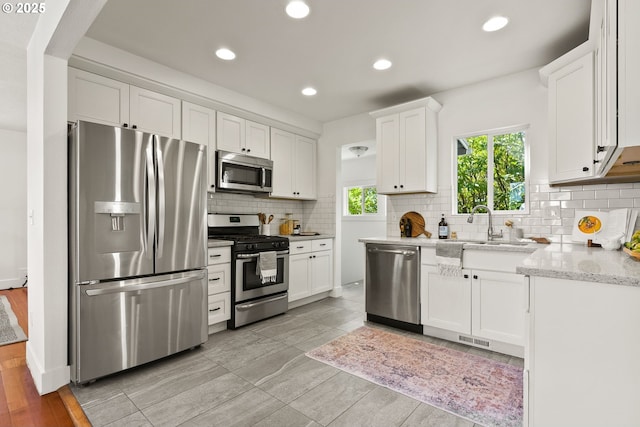 kitchen featuring visible vents, a sink, white cabinetry, decorative backsplash, and appliances with stainless steel finishes