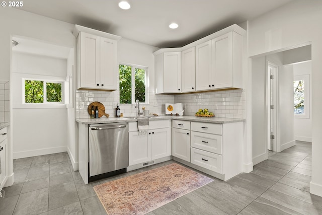 kitchen featuring a sink, stainless steel dishwasher, baseboards, and plenty of natural light