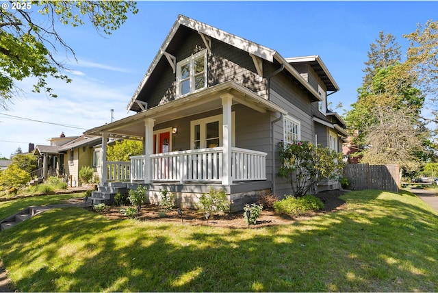 view of front facade featuring covered porch, fence, and a front lawn