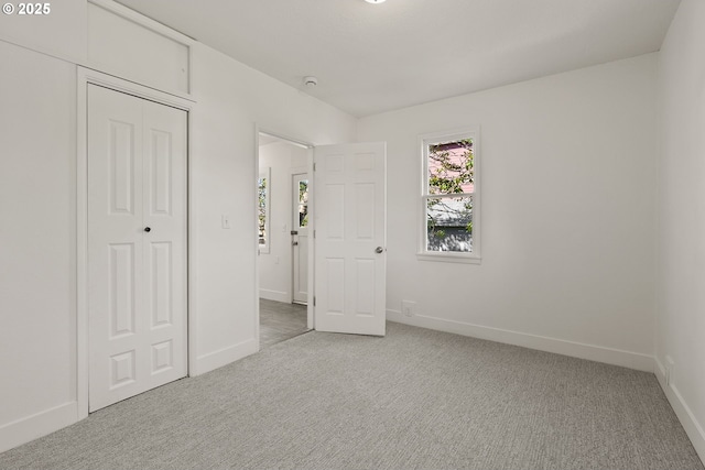 unfurnished bedroom with light carpet, baseboards, and a closet