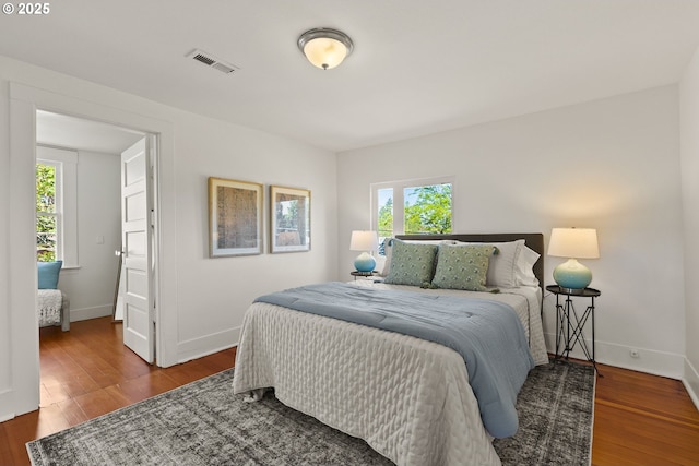 bedroom with wood finished floors, visible vents, and multiple windows