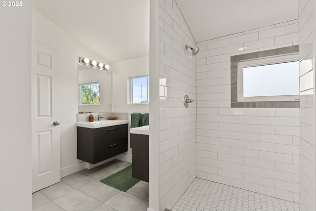 full bath featuring vanity, tile patterned flooring, lofted ceiling, and tiled shower