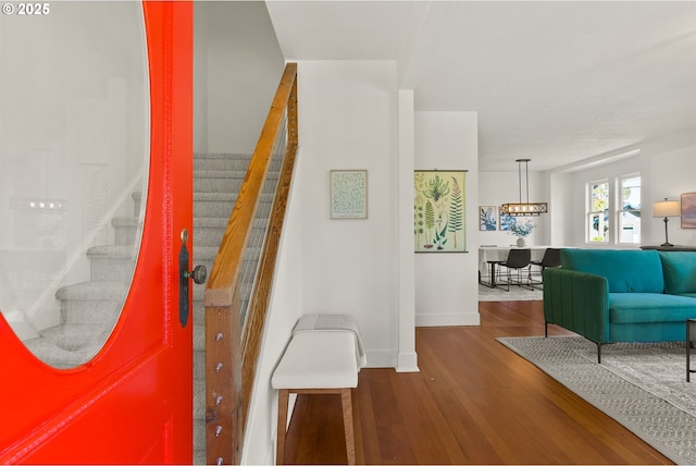 entryway featuring a notable chandelier, stairs, baseboards, and dark wood-style floors