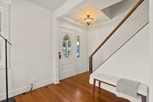 entrance foyer with a notable chandelier, baseboards, visible vents, wood finished floors, and stairway