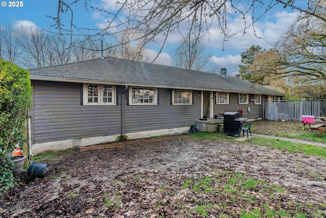 back of property featuring roof with shingles and fence